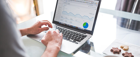 Person sitzt vor einem Laptop und tippt.